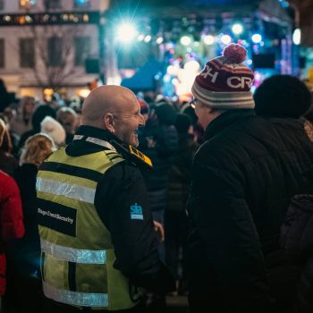 A friendly Stage Security guard talking to a member of the public at an event.