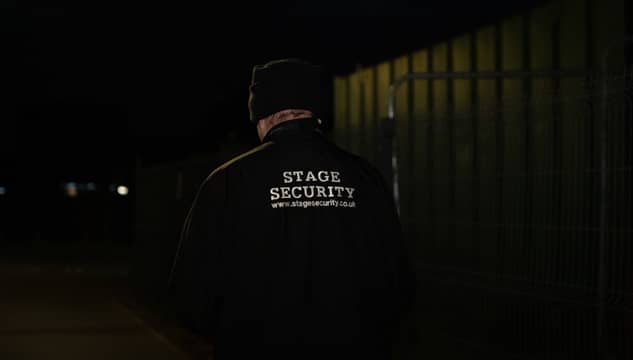 A Stage Security guard patrolling an area at night.